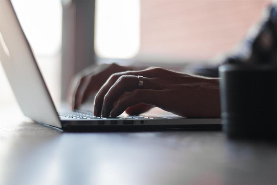 Hände, die am späten Abend auf einer Laptop-Tastatur arbeiten